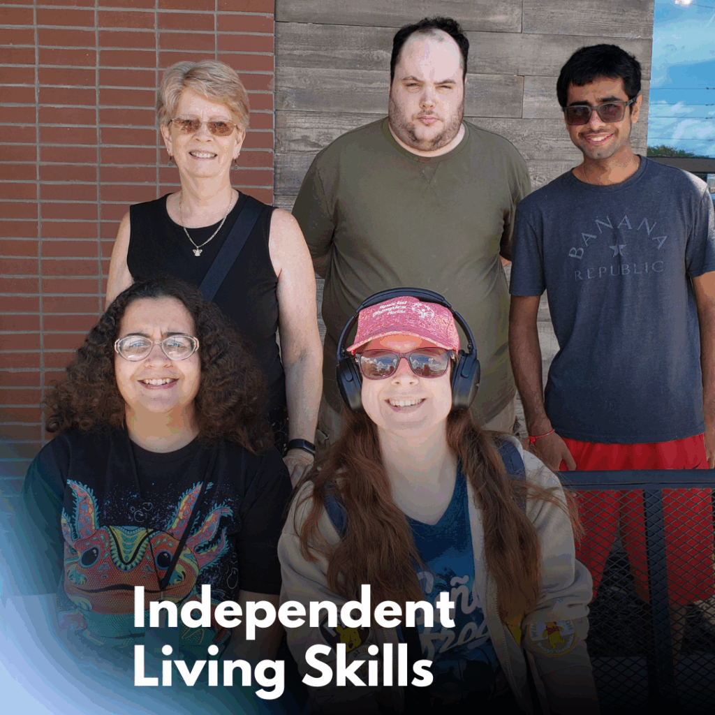 A group photo of five smiling people standing outside near a brick wall. Two are seated in front, wearing colorful shirts and accessories, while three stand behind them. The text overlay at the bottom reads “Independent Living Skills.”