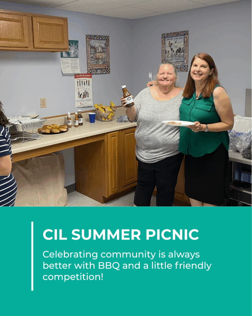 Two CIL staff members smile with BBQ food and sauce during the CIL Summer Picnic, standing by a counter of food.