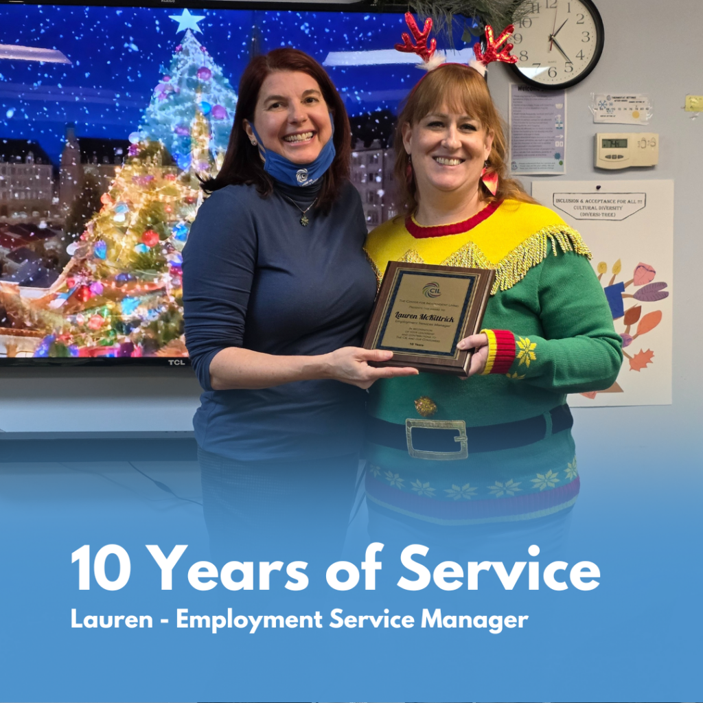 Amy and Lauren (CIL staff members) smile while holding a framed certificate recognizing Lauren’s 10 years of service as an Employment Service Manager during a holiday celebration.