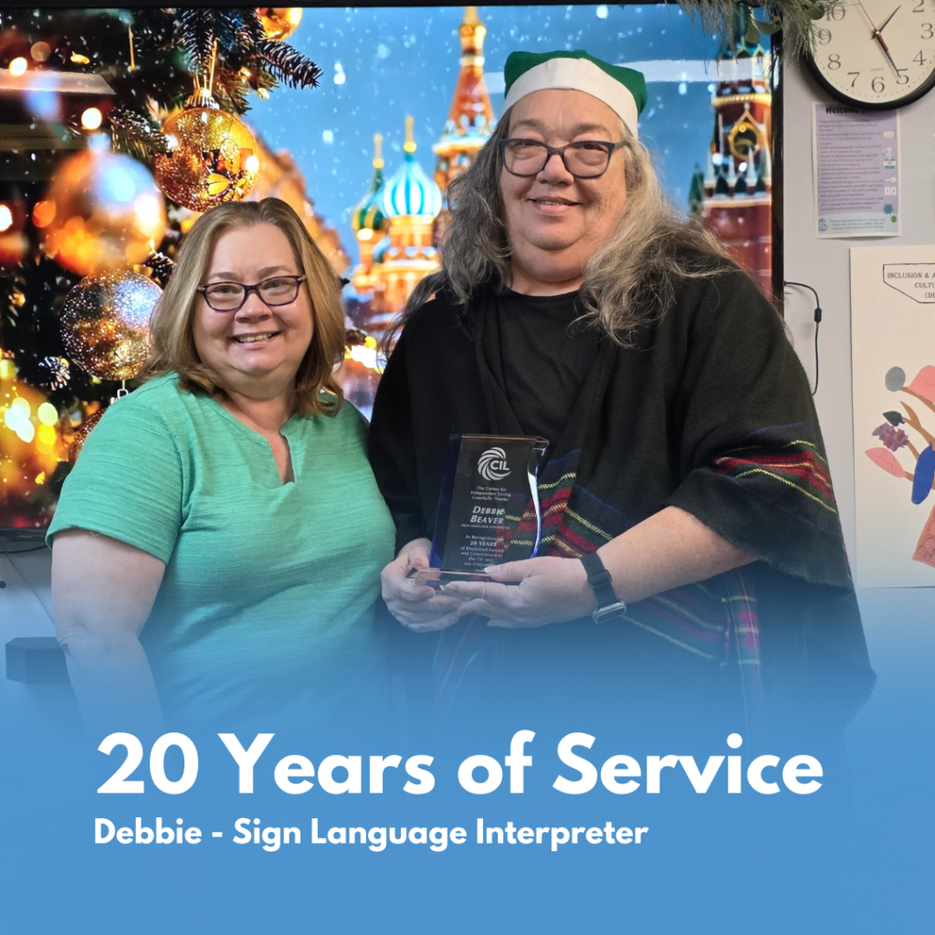 CIL staff members smile while holding a framed certificate recognizing Debbie’s 20 years of service as a Sign Language Interpreter during a holiday celebration.