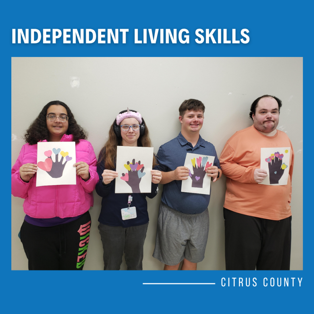 Four ILS participants in Citrus County holding handmade Valentine crafts featuring colorful heart designs on paper.
